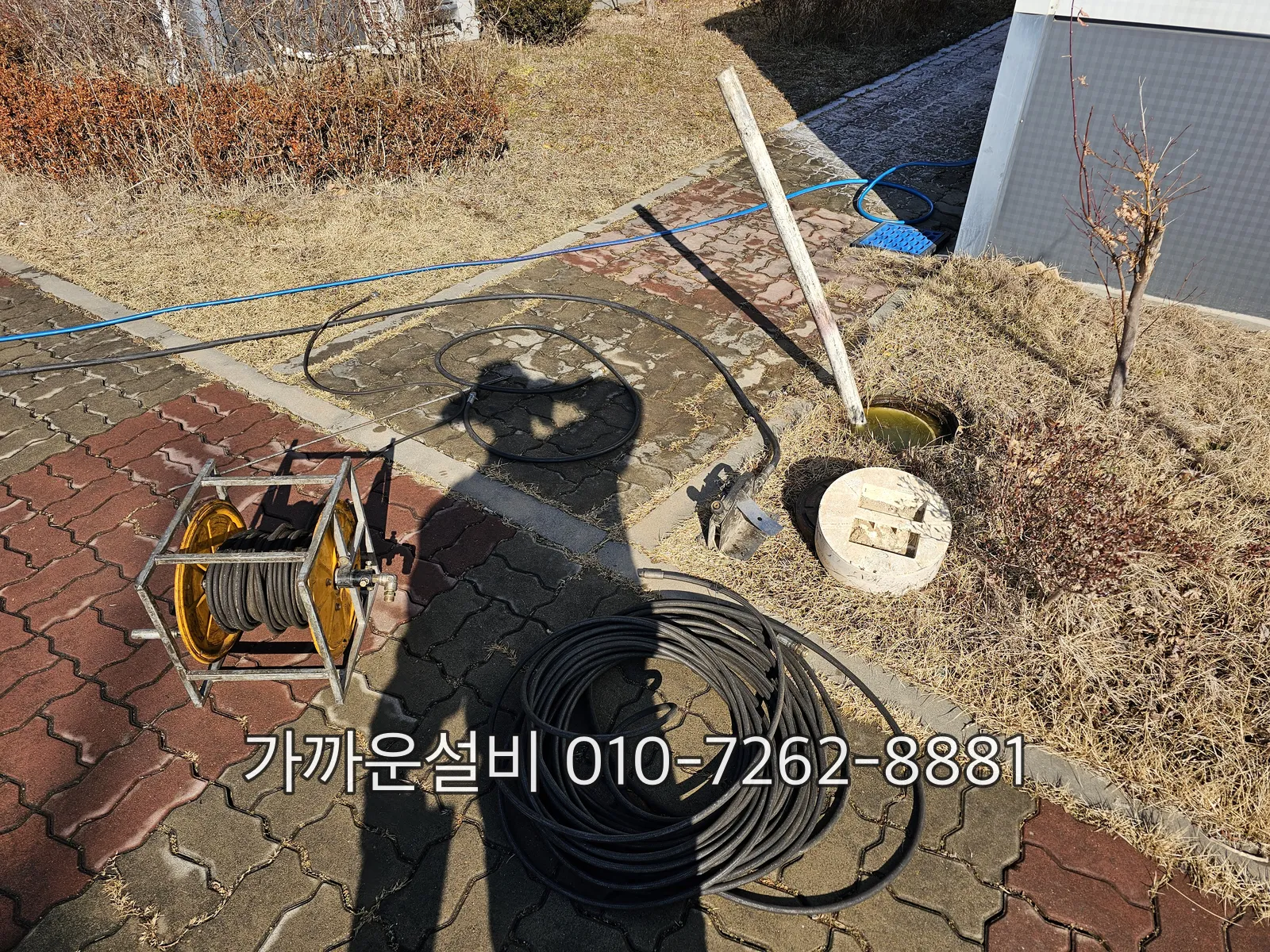 마당 옥외 우수 배관 청소구에 세척 케이블을 넣는 모습